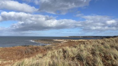 İskoçya 'da Edinburgh yakınlarındaki Aberlady Plajı. Açık bir bahar gününde rüzgârlı bir sahil. Hafif bulutlar, altın kum, silip süpüren sahil ve deniz kıyıları