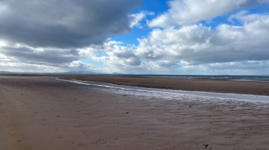 İskoçya 'da Edinburgh yakınlarındaki Aberlady Plajı. Açık bir bahar gününde rüzgârlı bir sahil. Hafif bulutlar, altın kum, silip süpüren sahil ve deniz kıyıları