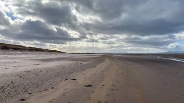 İskoçya 'da Edinburgh yakınlarındaki Aberlady Plajı. Açık bir bahar gününde rüzgârlı bir sahil. Hafif bulutlar, altın kum, silip süpüren sahil ve deniz kıyıları