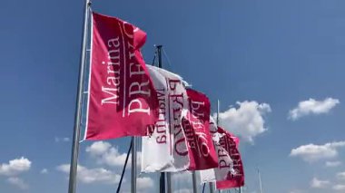 Lüks yat limanının girişinde rüzgarda uçuşan D-Marina bayrakları. Hırvatistan 'ın Zadar kenti yakınlarında Sukoan. Güneşli tatil beldesi ve turistik eğlence. Lüks tekneler ve güneşte yaşam tarzı