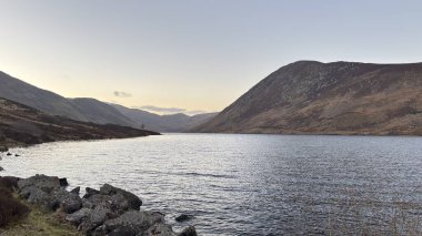 İskoçya 'nın dağlık kırsal kesimindeki göl tareti İskoçya' nın dağlık arazi manzarası tipik kenevir ve otlaklarla kaplı.