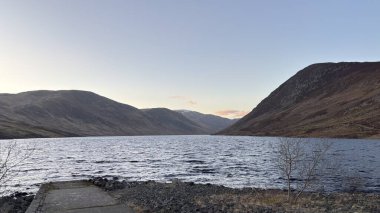İskoçya 'nın dağlık kırsal kesimindeki göl tareti İskoçya' nın dağlık arazi manzarası tipik kenevir ve otlaklarla kaplı.