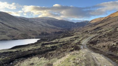 İskoçya 'nın dağlık kırsal kesimindeki göl tareti İskoçya' nın dağlık arazi manzarası tipik kenevir ve otlaklarla kaplı.