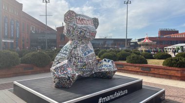 Manufaktura alışveriş merkezindeki süslü oyuncak ayının anıtı. Polonya, Lodz 'daki şehir sokak manzarası. Bu Polonya kasabasında mimarlık, binalar ve dükkanlar var.. 