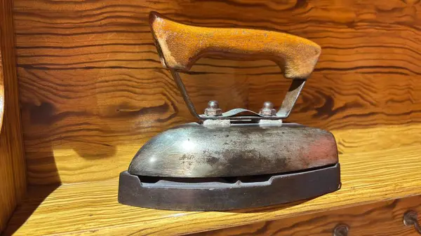 Giysiler için ahşap saplı klasik metal demir. Ahşap bir rafta eski Sovyet tasarımı
