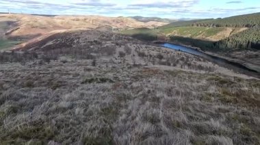 Glen Devon 'da Perthshire' daki Loch Tarret Barajı 'nın yanında yürüyorum. İskoç kırları ve tepeleri. Dağ sırası. Otlaklar, koyunlar ve akan su. İskoçya İskoç nehri aydınlık güneşli bir günde vahşi yerleri yakar.