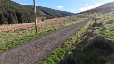 Glen Devon 'da Perthshire' daki Loch Tarret Barajı 'nın yanında yürüyorum. İskoç kırları ve tepeleri. Dağ sırası. Otlaklar, koyunlar ve akan su. İskoçya İskoç nehri aydınlık güneşli bir günde vahşi yerleri yakar.