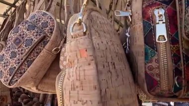 Portekiz 'in Algarve kıyısındaki eski Lagos kasabasının merkezinde satılık bir dükkanda asılı geleneksel mantar el çantaları. Parlak güneşli bir gün Rüzgarda ilerliyor