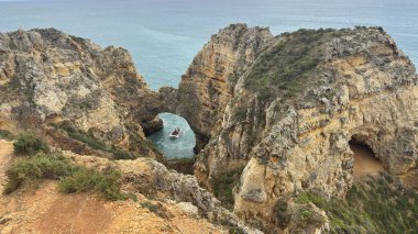 Lagos yakınlarındaki Portekiz 'in Algarve sahil şeridinde güzel sahil kayalıkları, kayalar ve plajlar. Okyanus dalgaları kumtaşı yapıları turistik eğlence mağaraları geziler kumsal hayatı kumları.