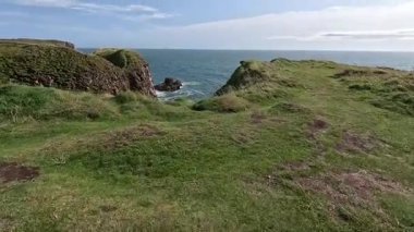 Buchan Bullers uçurumun kenarında yürüyor. Güzel İskoç engebeli kıyı şeridi Kuzey Denizi yamacı yaz güneşinin altında