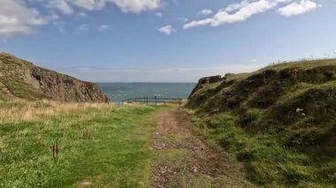 Buchan Bullers uçurumun kenarında yürüyor. Güzel İskoç engebeli kıyı şeridi Kuzey Denizi yamacı yaz güneşinin altında