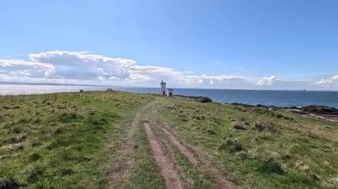 Elie Ness 'teki beyaz deniz feneri deniz, navigasyon ve miras temalı dramatik kıyı manzaralı.