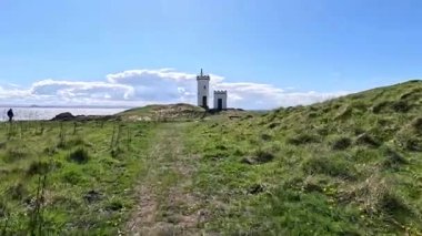 Elie Ness 'teki beyaz deniz feneri deniz, navigasyon ve miras temalı dramatik kıyı manzaralı.