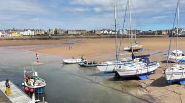 Mavi gökyüzü klasiği İskoç sahil cazibesi ve deniz atmosferi altında Elie Limanı 'na yanaşan tekneler..