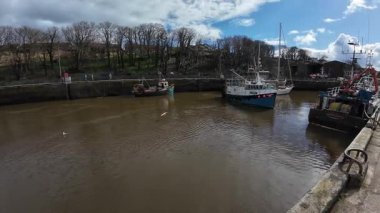 Eyemouth Limanı 'na kıyı manzaralı tekneler yanaştı. Çalışan bir balıkçı limanı ve tarihi deniz cazibesini yansıtıyor.
