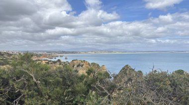 Lagos yakınlarındaki çarpıcı Algarve kıyı şeridi dramatik uçurumlar, altın plajlar, turkuaz sular ve parlak bir gökyüzü altında manzaralı okyanus manzarası.