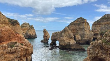 Lagos yakınlarındaki çarpıcı Algarve kıyı şeridi dramatik uçurumlar, altın plajlar, turkuaz sular ve parlak bir gökyüzü altında manzaralı okyanus manzarası.