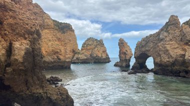Lagos yakınlarındaki çarpıcı Algarve kıyı şeridi dramatik uçurumlar, altın plajlar, turkuaz sular ve parlak bir gökyüzü altında manzaralı okyanus manzarası.