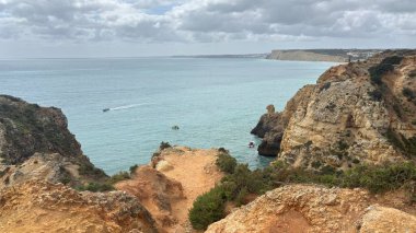Lagos yakınlarındaki çarpıcı Algarve kıyı şeridi dramatik uçurumlar, altın plajlar, turkuaz sular ve parlak bir gökyüzü altında manzaralı okyanus manzarası.