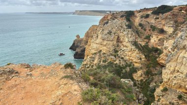 Lagos yakınlarındaki çarpıcı Algarve kıyı şeridi dramatik uçurumlar, altın plajlar, turkuaz sular ve parlak bir gökyüzü altında manzaralı okyanus manzarası.