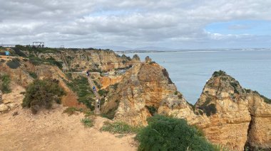 Lagos yakınlarındaki çarpıcı Algarve kıyı şeridi dramatik uçurumlar, altın plajlar, turkuaz sular ve parlak bir gökyüzü altında manzaralı okyanus manzarası.