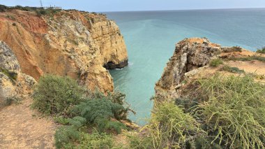 Lagos yakınlarındaki çarpıcı Algarve kıyı şeridi dramatik uçurumlar, altın plajlar, turkuaz sular ve parlak bir gökyüzü altında manzaralı okyanus manzarası.