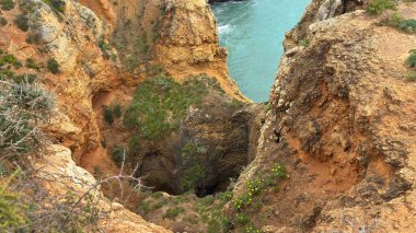Lagos yakınlarındaki çarpıcı Algarve kıyı şeridi dramatik uçurumlar, altın plajlar, turkuaz sular ve parlak bir gökyüzü altında manzaralı okyanus manzarası.