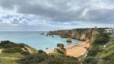 Lagos yakınlarındaki çarpıcı Algarve kıyı şeridi dramatik uçurumlar, altın plajlar, turkuaz sular ve parlak bir gökyüzü altında manzaralı okyanus manzarası.