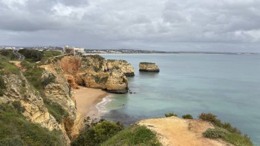 Lagos yakınlarındaki çarpıcı Algarve kıyı şeridi dramatik uçurumlar, altın plajlar, turkuaz sular ve parlak bir gökyüzü altında manzaralı okyanus manzarası.