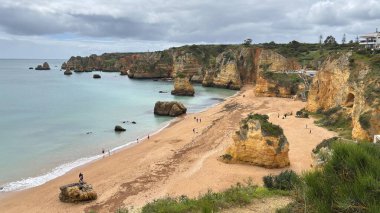 Lagos yakınlarındaki çarpıcı Algarve kıyı şeridi dramatik uçurumlar, altın plajlar, turkuaz sular ve parlak bir gökyüzü altında manzaralı okyanus manzarası.