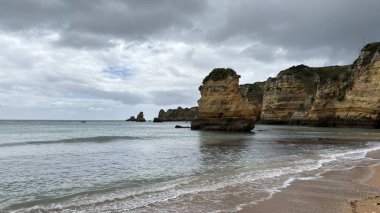 Lagos yakınlarındaki çarpıcı Algarve kıyı şeridi dramatik uçurumlar, altın plajlar, turkuaz sular ve parlak bir gökyüzü altında manzaralı okyanus manzarası.