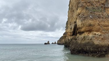 Lagos yakınlarındaki çarpıcı Algarve kıyı şeridi dramatik uçurumlar, altın plajlar, turkuaz sular ve parlak bir gökyüzü altında manzaralı okyanus manzarası.