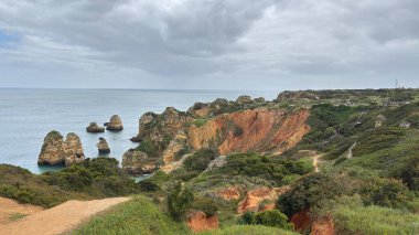 Lagos yakınlarındaki çarpıcı Algarve kıyı şeridi dramatik uçurumlar, altın plajlar, turkuaz sular ve parlak bir gökyüzü altında manzaralı okyanus manzarası.