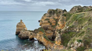 Lagos yakınlarındaki çarpıcı Algarve kıyı şeridi dramatik uçurumlar, altın plajlar, turkuaz sular ve parlak bir gökyüzü altında manzaralı okyanus manzarası.
