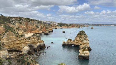 Lagos yakınlarındaki çarpıcı Algarve kıyı şeridi dramatik uçurumlar, altın plajlar, turkuaz sular ve parlak bir gökyüzü altında manzaralı okyanus manzarası.