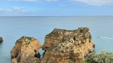 Lagos yakınlarındaki çarpıcı Algarve kıyı şeridi dramatik uçurumlar, altın plajlar, turkuaz sular ve parlak bir gökyüzü altında manzaralı okyanus manzarası.