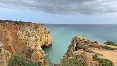 Lagos yakınlarındaki çarpıcı Algarve kıyı şeridi dramatik uçurumlar, altın plajlar, turkuaz sular ve parlak bir gökyüzü altında manzaralı okyanus manzarası.