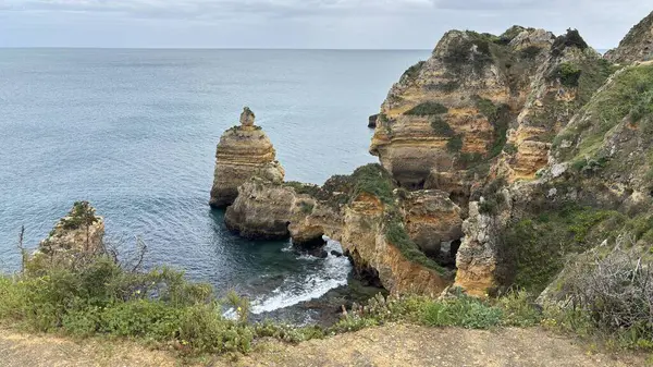 Lagos yakınlarındaki çarpıcı Algarve kıyı şeridi dramatik uçurumlar, altın plajlar, turkuaz sular ve parlak bir gökyüzü altında manzaralı okyanus manzarası.