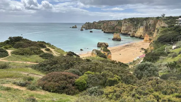 Lagos yakınlarındaki çarpıcı Algarve kıyı şeridi dramatik uçurumlar, altın plajlar, turkuaz sular ve parlak bir gökyüzü altında manzaralı okyanus manzarası.