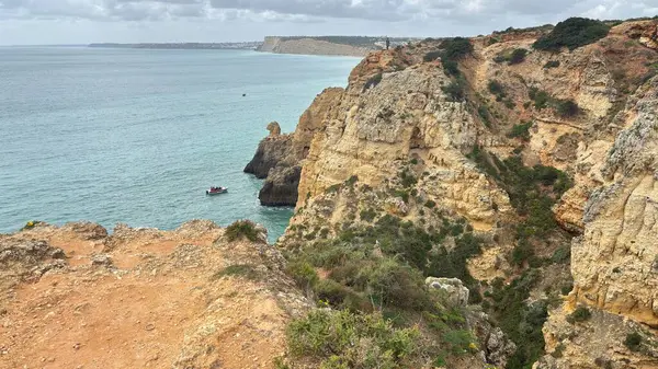 Lagos yakınlarındaki çarpıcı Algarve kıyı şeridi dramatik uçurumlar, altın plajlar, turkuaz sular ve parlak bir gökyüzü altında manzaralı okyanus manzarası.