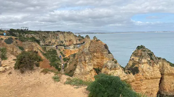 Lagos yakınlarındaki çarpıcı Algarve kıyı şeridi dramatik uçurumlar, altın plajlar, turkuaz sular ve parlak bir gökyüzü altında manzaralı okyanus manzarası.