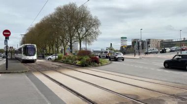 Nantes kentsel caddelerinde faaliyet gösteren modern Fransız yolcu tramvaylarının sokak seviyesindeki görüntüsü günlük hareketle toplu taşımayı gösteriyor.