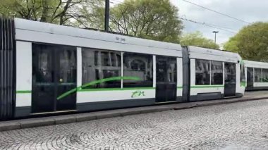 Nantes kentsel caddelerinde faaliyet gösteren modern Fransız yolcu tramvaylarının sokak seviyesindeki görüntüsü günlük hareketle toplu taşımayı gösteriyor.