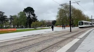 Nantes kentsel caddelerinde faaliyet gösteren modern Fransız yolcu tramvaylarının sokak seviyesindeki görüntüsü günlük hareketle toplu taşımayı gösteriyor.
