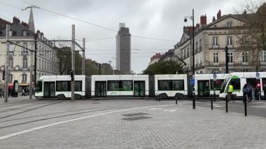 Nantes kentsel caddelerinde faaliyet gösteren modern Fransız yolcu tramvaylarının sokak seviyesindeki görüntüsü günlük hareketle toplu taşımayı gösteriyor.