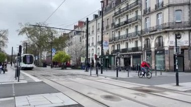 Nantes kentsel caddelerinde faaliyet gösteren modern Fransız yolcu tramvaylarının sokak seviyesindeki görüntüsü günlük hareketle toplu taşımayı gösteriyor.
