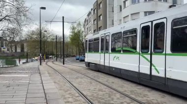 Nantes kentsel caddelerinde faaliyet gösteren modern Fransız yolcu tramvaylarının sokak seviyesindeki görüntüsü günlük hareketle toplu taşımayı gösteriyor.