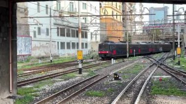 İtalyan yolcu trenleri istasyonlarda ve Napoli 'deki raylar boyunca hareket halinde, güneydeki bir şehir merkezinde toplu taşıma ve demiryolu ulaşımını yakalıyor.