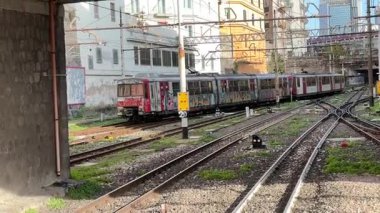 İtalyan yolcu trenleri istasyonlarda ve Napoli 'deki raylar boyunca hareket halinde, güneydeki bir şehir merkezinde toplu taşıma ve demiryolu ulaşımını yakalıyor.