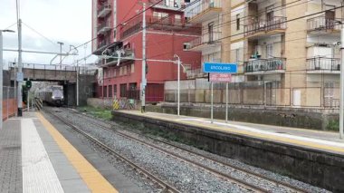 İtalyan yolcu trenleri istasyonlarda ve Napoli 'deki raylar boyunca hareket halinde, güneydeki bir şehir merkezinde toplu taşıma ve demiryolu ulaşımını yakalıyor.